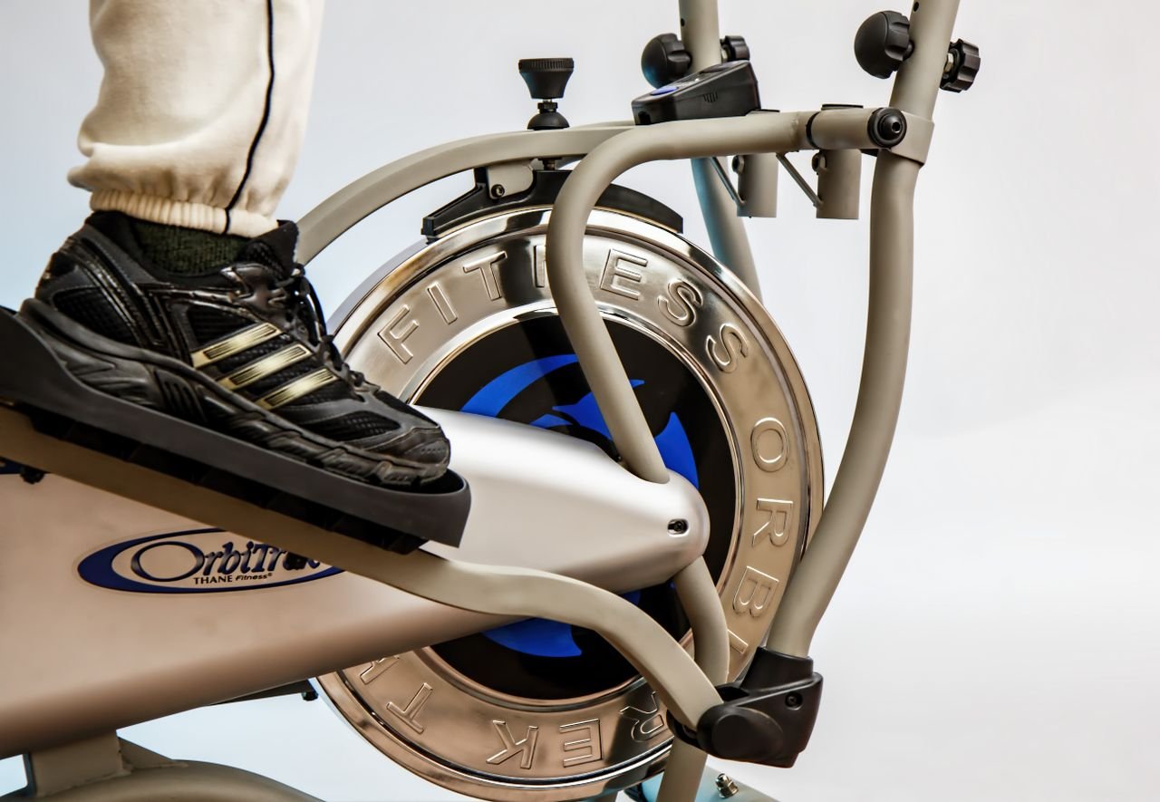 Services Foot on pedal of elliptical trainer showcasing fitness equipment and footwear close-up.