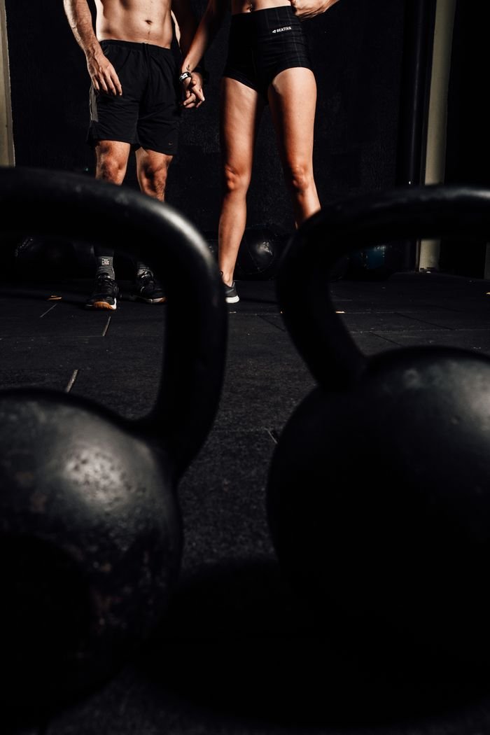 Services Man and woman in gym with kettlebells, embracing a healthy lifestyle.