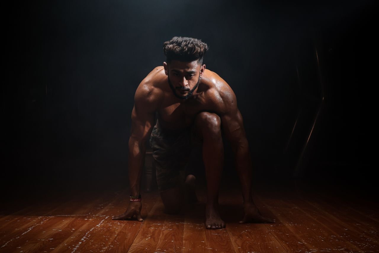 Home Dynamic image of a muscular man in a kneeling start position, highlighting strength and focus.