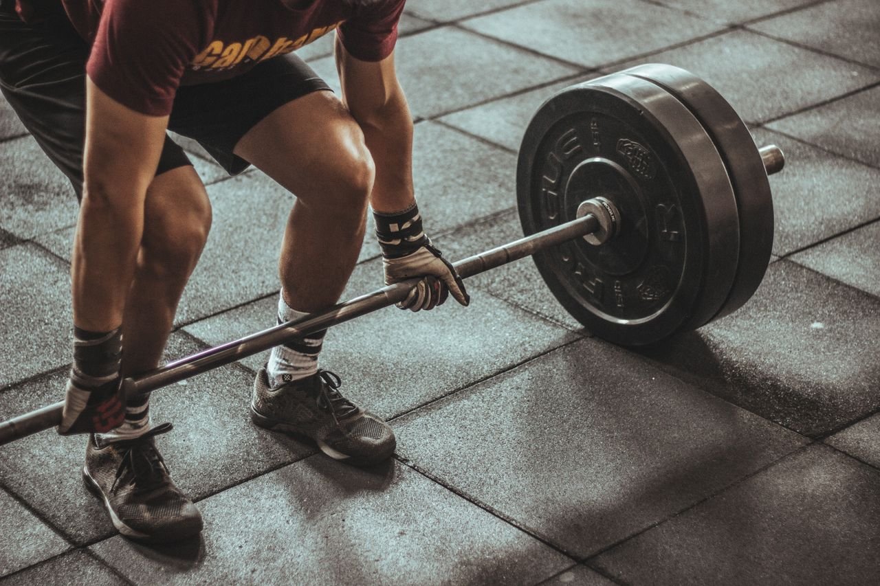 Home A focused weightlifter prepares to lift a heavy barbell in an indoor gym setting.
